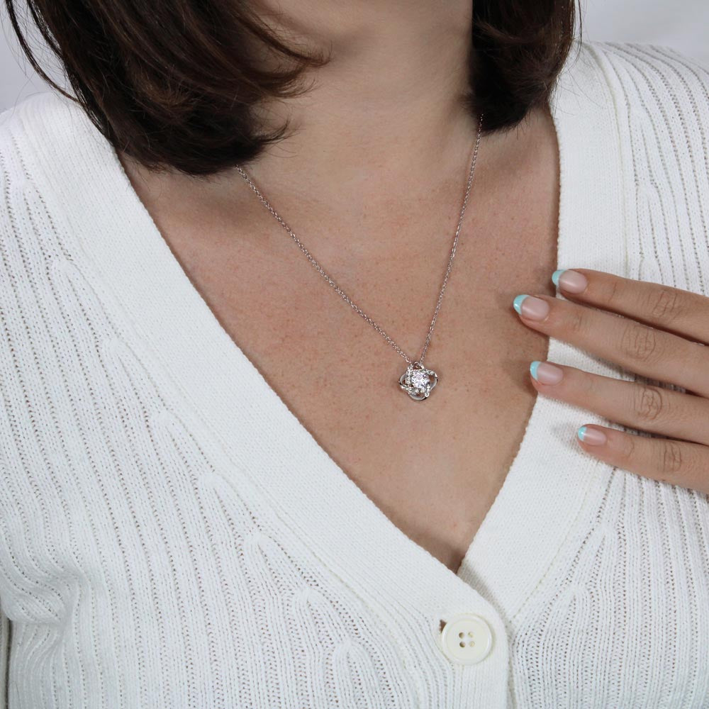 Original white gold finish knot necklace worn on a white knit top to show pendant scale