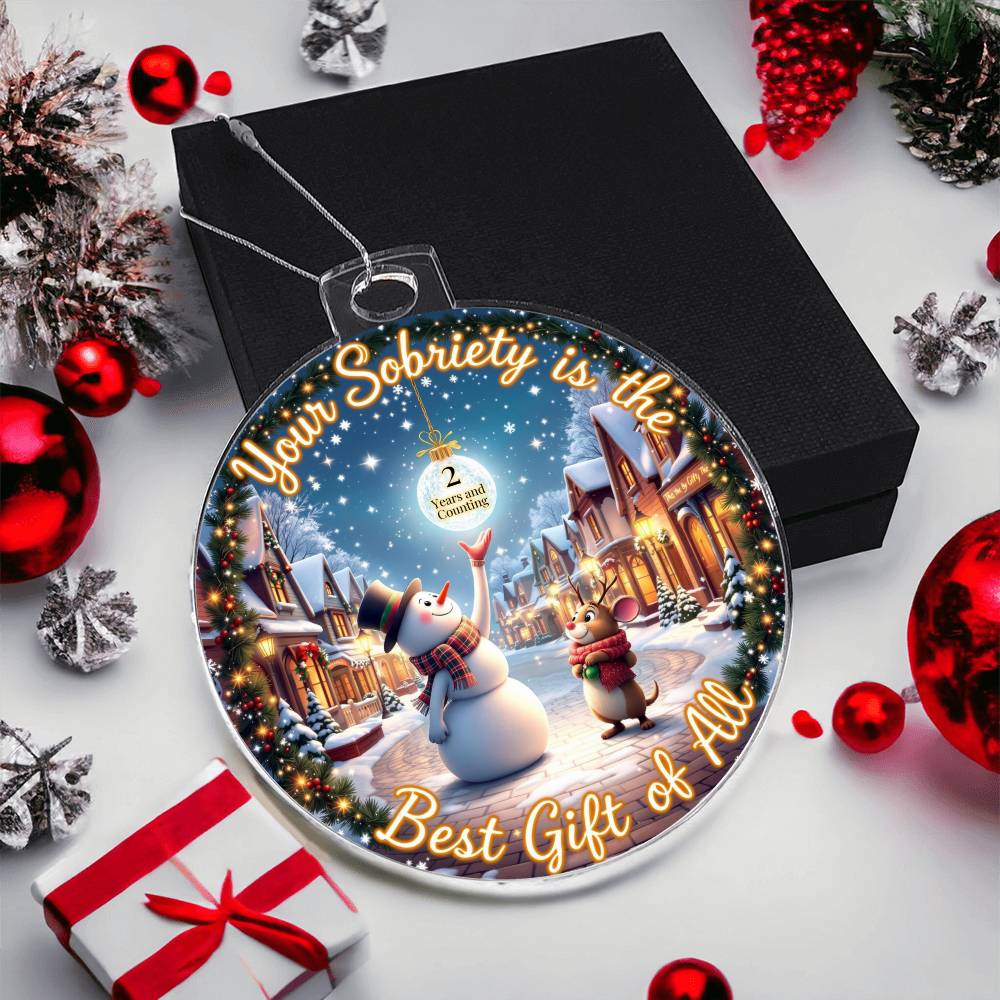Circular acrylic bulb ornament on black gift box with snowman winter scene and gold border