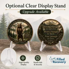 Pair of sobriety coins with bear-and-mountains designs, each on a clear display stand