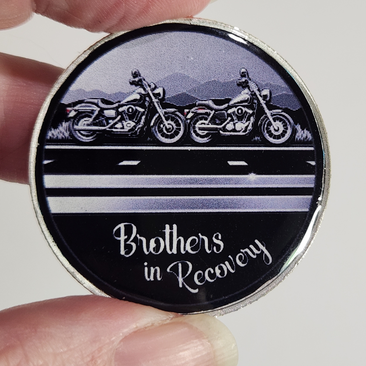 Close-up sobriety coin with motorcycle illustration and 'Brothers in Recovery' text