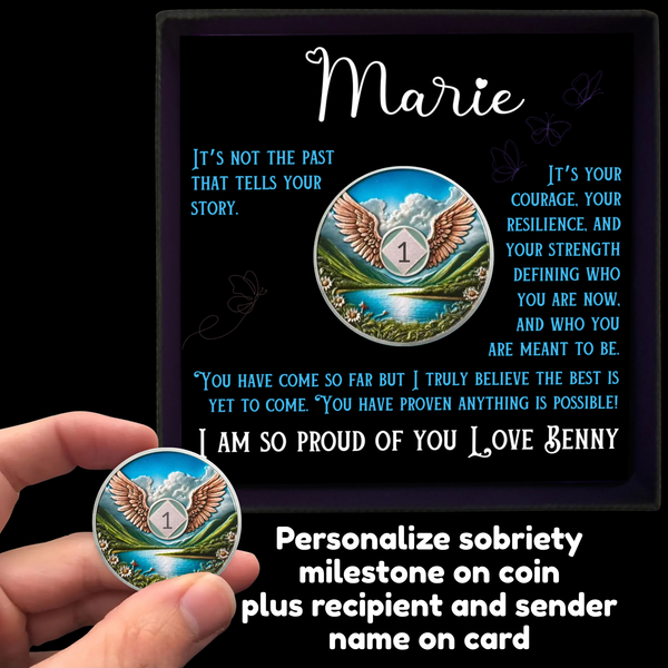 Personalized sobriety coin with winged emblem, held beside gift box and card