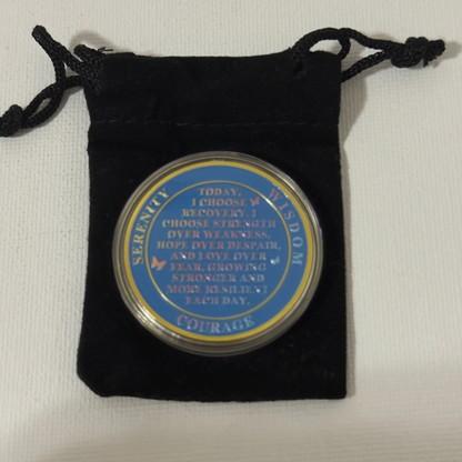 Sobriety coin in black velvet drawstring pouch, blue text side visible, gold edging