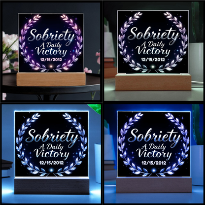Square LED plaque on wood base with laurel wreath glowing in blue and purple.