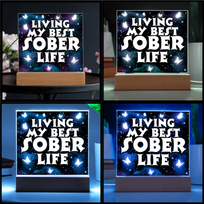 Square LED acrylic plaque on wood base showing multiple LED colors for "Living My Best Sober Life".