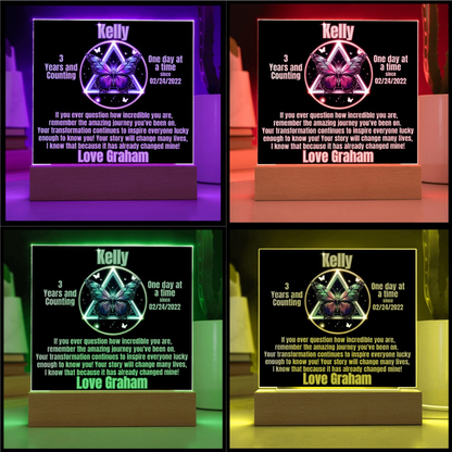 Personalized LED milestone plaque showing multicolor glowing butterfly emblem on wooden base