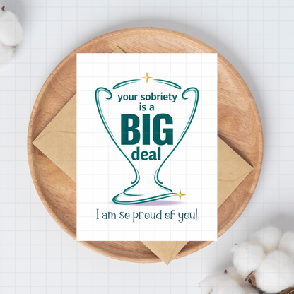Sobriety encouragement card with teal 'Big deal' heart, on kraft envelope.