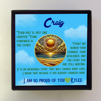 Black gift box with blue greeting card featuring Craig and gold sun-over-ocean coin