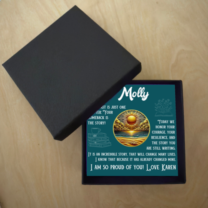 Black gift box with teal sobriety card featuring sunburst-ocean artwork and 'Molly'.