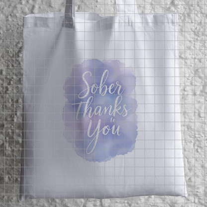Translucent tote bag with "Sober Thanks to You" script print on a blue watercolor circle