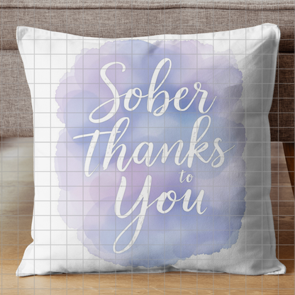 Light blue throw pillow with "Sober Thanks to You" script text in a watercolor circle