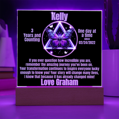 Personalized LED milestone plaque with purple glowing butterfly emblem on wooden base