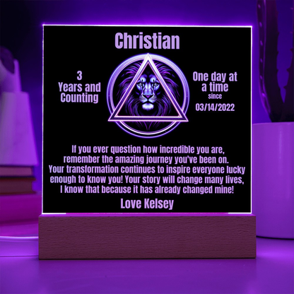 Square LED plaque on wood base glowing with Christian triangle lion design and message