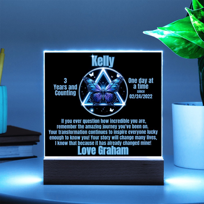 Personalized LED milestone plaque with green glowing butterfly emblem on wooden base