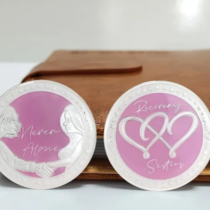 Two silver coins with purple centers showing angel figures and “Never Alone” text