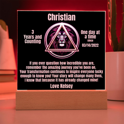 Square LED plaque on wood base glowing with Christian triangle lion and message
