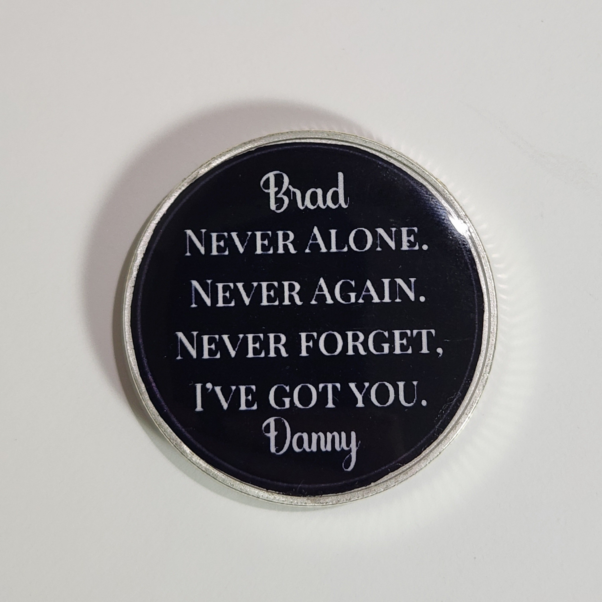 Sobriety coin with 'Brad' and quote 'Never alone...' in white lettering