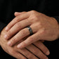 Close-up of hands wearing a silver-tone engraved band ring