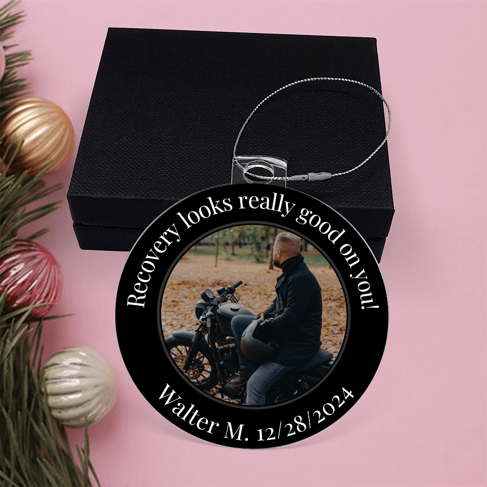 Round acrylic recovery photo ornament over a black gift box with silver hanging chain