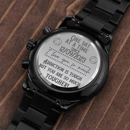 Engraved caseback and metal bracelet of a black chronograph watch on wood