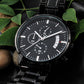 Black chronograph wristwatch with metal link bracelet, close-up of black dial