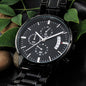 Black chronograph watch close-up with black dial, subdials, and date window