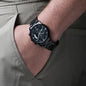 Black chronograph watch on wrist with metal link bracelet