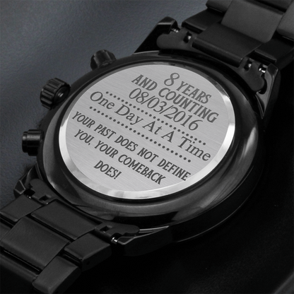 Black men’s chronograph wristwatch with engraved case back cover text