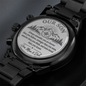 Engraved watch back disc on black metal link bracelet with chronograph dials beneath