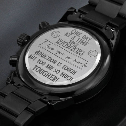 Engraved caseback on a black chronograph watch with metal bracelet