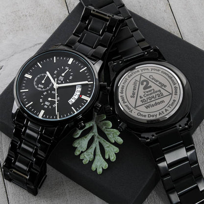 Black recovery watch on dark box lid with linked metal bracelet and round dial