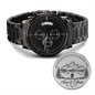 Black metal chronograph-style wristwatch with engraved round caseback coin