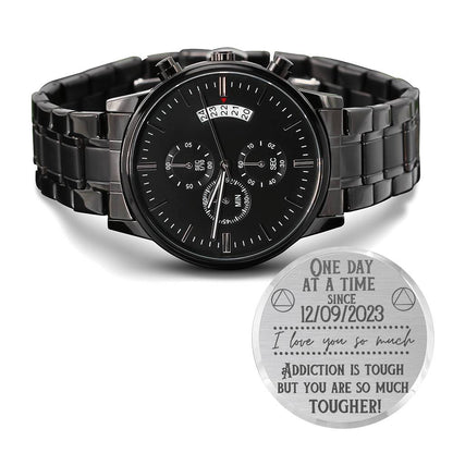 Black chronograph watch on metal bracelet with engraved medallion-style caseback