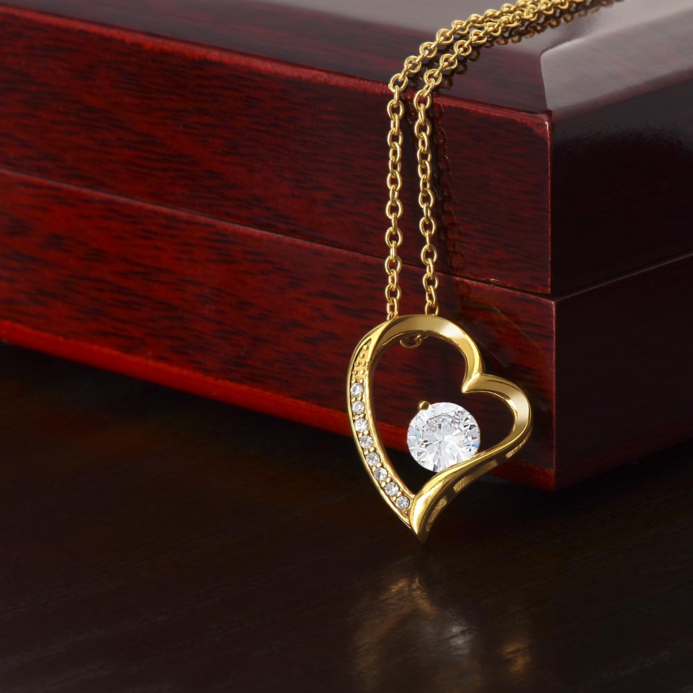 Gold heart pendant necklace with round center stone and crystal details, on chain