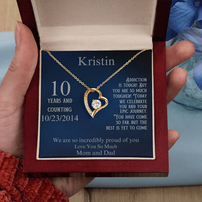 Gold heart pendant necklace in open gift box held in hand, with 10 years date 10/23/2014