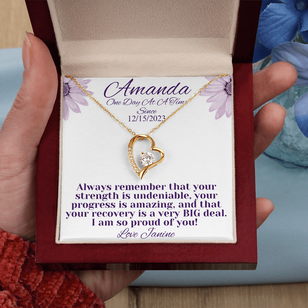 Gold heart recovery necklace with round center stone in red gift box, held
