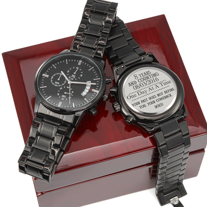 Black men’s chronograph wristwatch pair on red box, metal link bands
