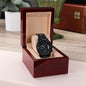 Black chronograph wristwatch in open wooden gift box with beige padded insert