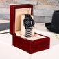 Black chronograph watch in red-and-cream presentation box with metal link band