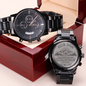 Black chronograph watch and engraved keepsake charm on dark red wooden gift box