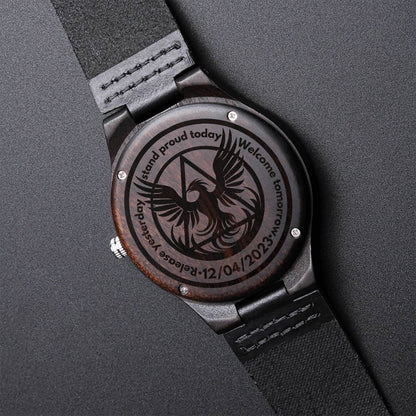 Engraved wood watch with dark round case, black leather strap, phoenix engraved dial face.