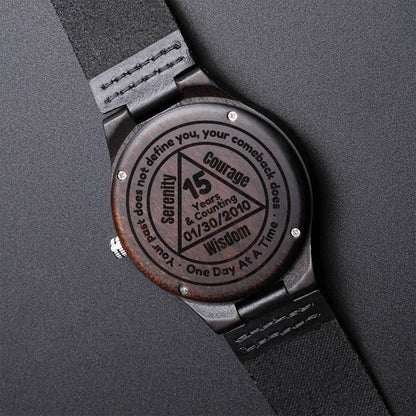 Engraved back of wood watch with black leather strap, circular message and bezel screws
