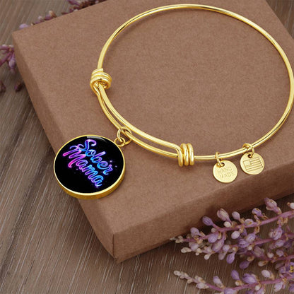 Gold bangle bracelet with “Sober Mama” round charm and small metal tags