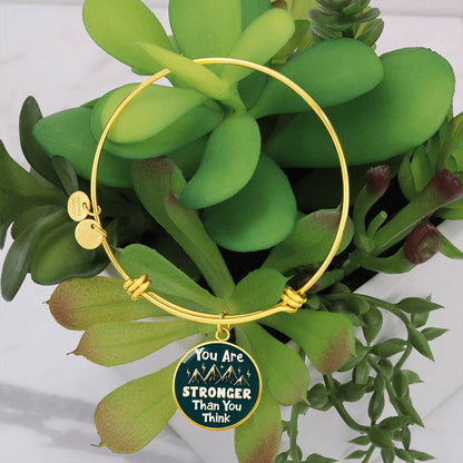Gold bangle bracelet with round teal charm pendant and two small round metal tags