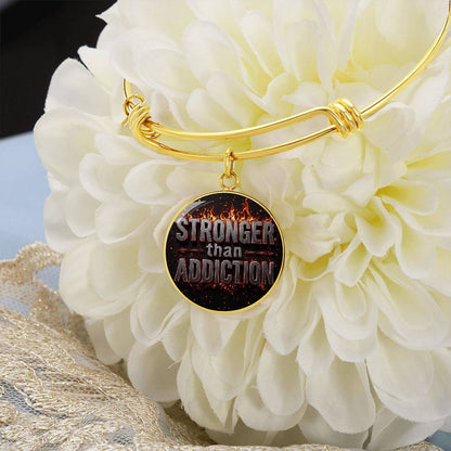 Gold bangle bracelet with round black statement charm hanging from flower display
