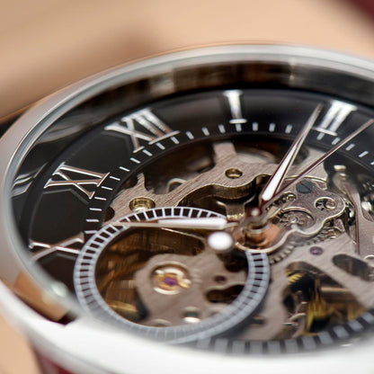 Close-up of openwork watch movement with Roman numerals on dark dial.