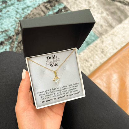 Gold-tone teardrop pendant necklace with round crystal center on chain.