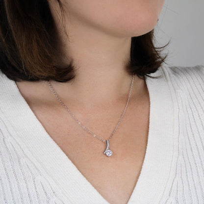 Silver-tone necklace with teardrop CZ pendant, close-up on collar