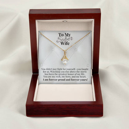 Gold-tone teardrop pendant necklace with round crystal center in open gift box.