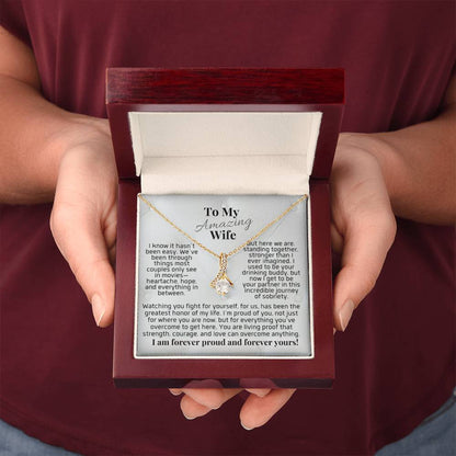 Silver-tone pendant necklace in gift box held in hands, teardrop charm with clear stones