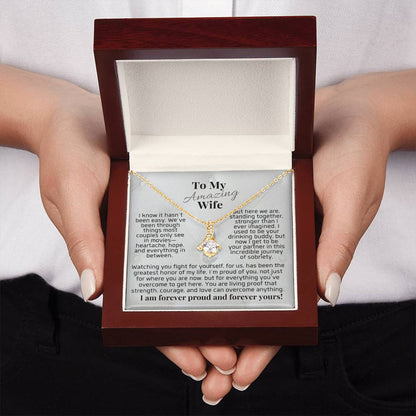 Silver-tone pendant necklace in open gift box held by hands, teardrop charm